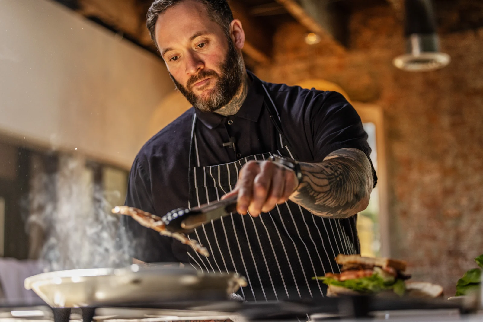 A chef turns MyBacon with tongs over a hot pan