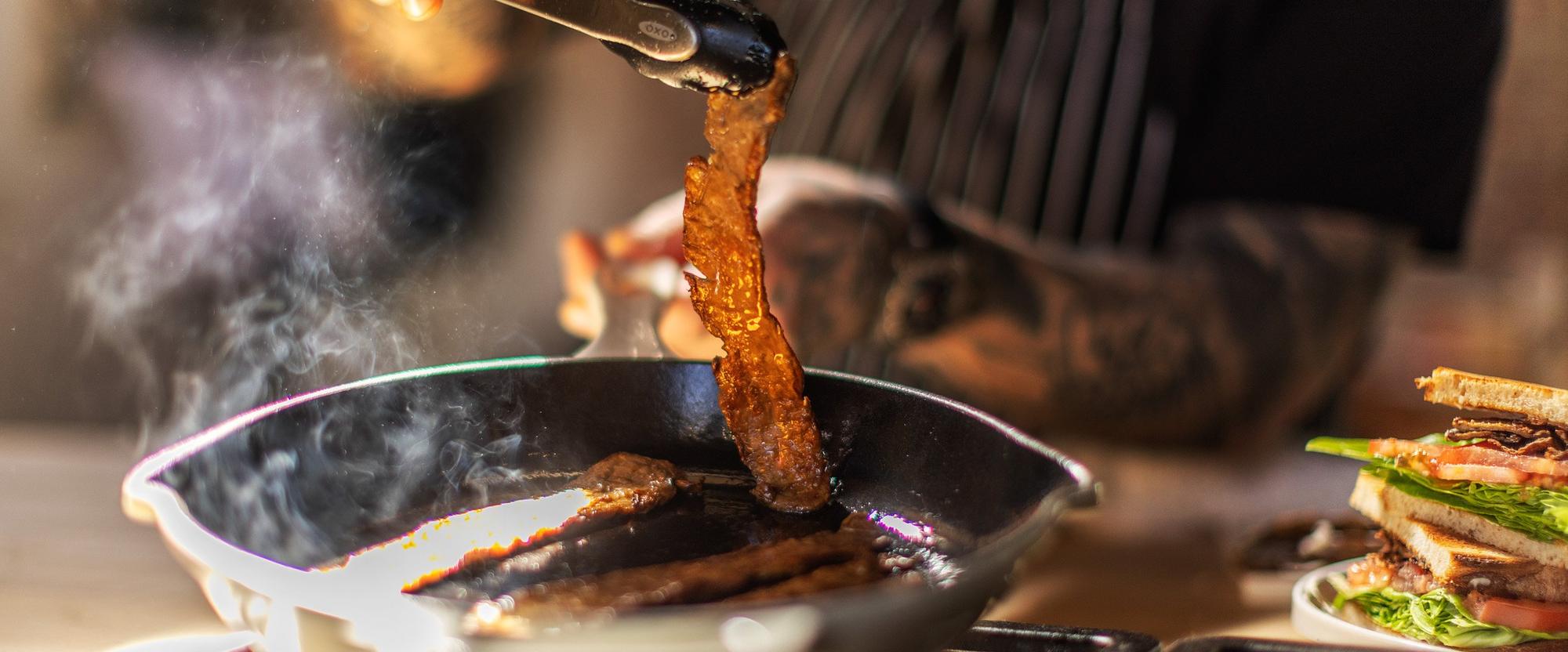 MyBacon cooking in a cast-iron skillet